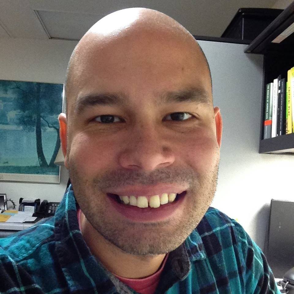 A photograph of Dr Aaron Trammell, sitting in an office and looking directly at the camera.